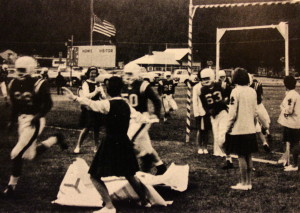 The Wolverines have been running through the cheerleader's signs from the North End Zone for over 50 years. Also a good look at the old school score board. Also, off in the distance is the old PUD building. 